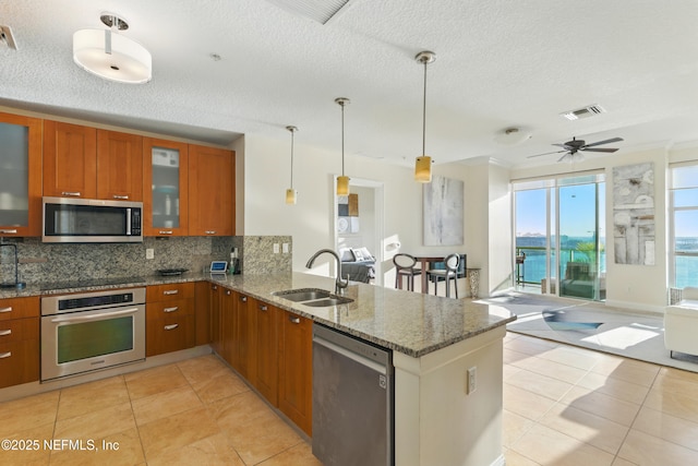 kitchen featuring visible vents, brown cabinets, a sink, stainless steel appliances, and a peninsula