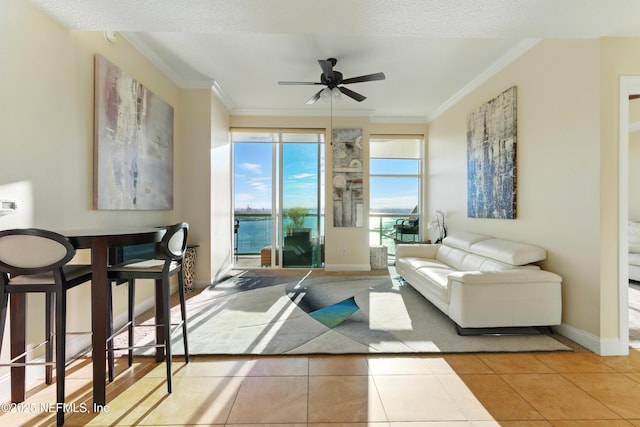 tiled living area featuring baseboards, ceiling fan, and ornamental molding