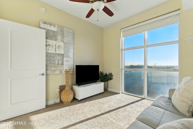 carpeted living room with baseboards and ceiling fan