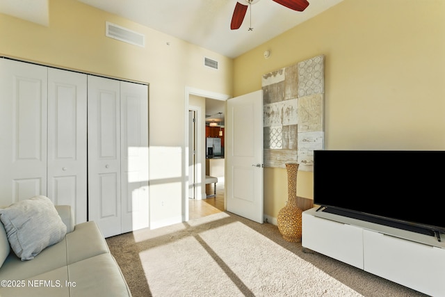 carpeted living area featuring visible vents and ceiling fan