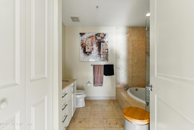 full bath with tiled bath, visible vents, baseboards, toilet, and vanity