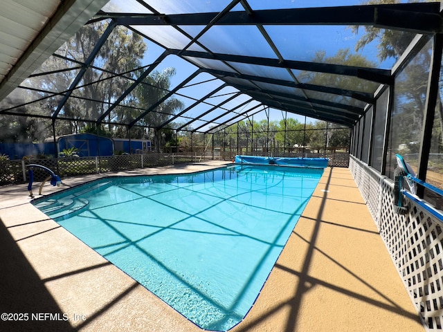 view of pool featuring an outbuilding, a covered pool, fence, a storage shed, and a lanai