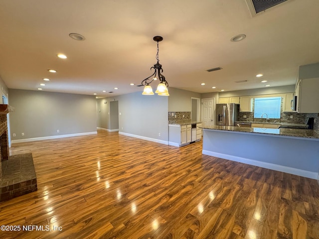 kitchen featuring visible vents, a sink, stainless steel appliances, dark wood-type flooring, and tasteful backsplash