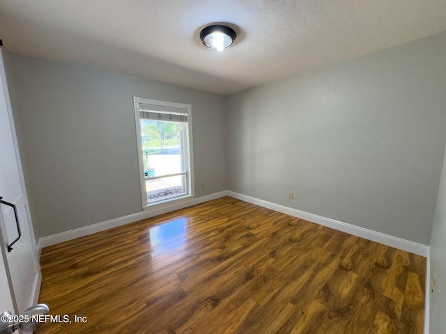 spare room with dark wood-style floors and baseboards