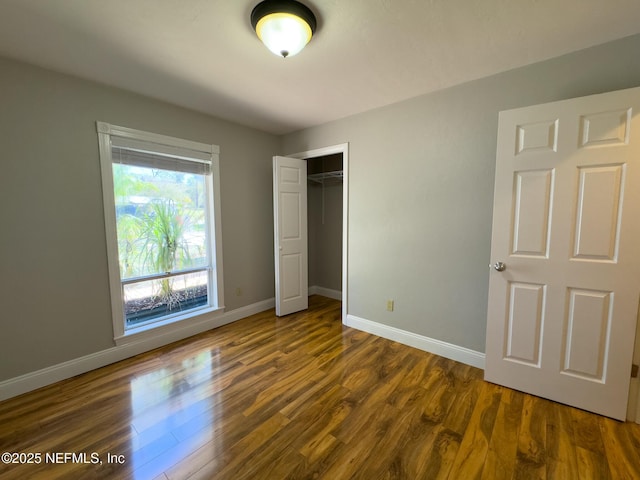 unfurnished bedroom with dark wood-type flooring and baseboards