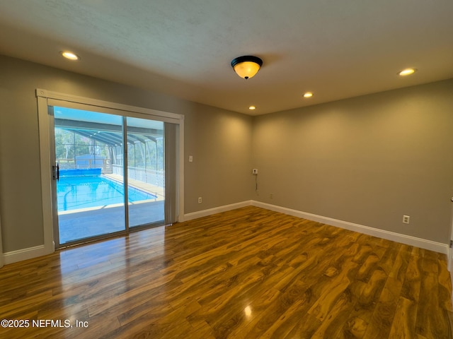 spare room featuring recessed lighting, dark wood-type flooring, and baseboards