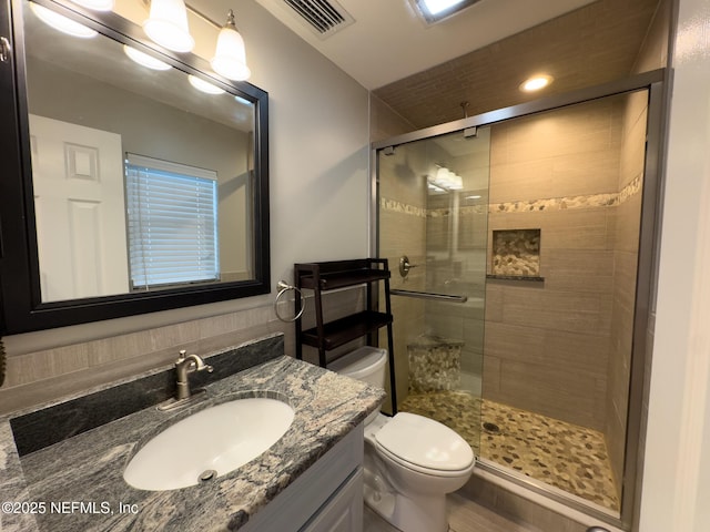 bathroom featuring visible vents, a shower stall, toilet, and vanity