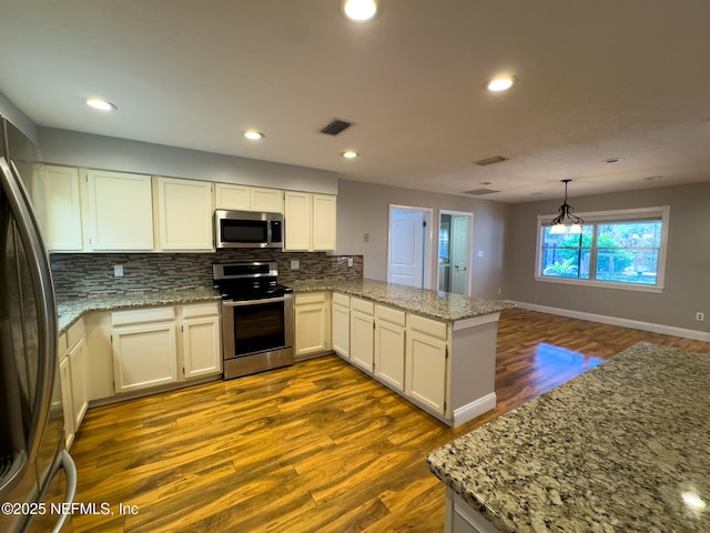 kitchen with dark wood-style floors, a peninsula, appliances with stainless steel finishes, tasteful backsplash, and a chandelier