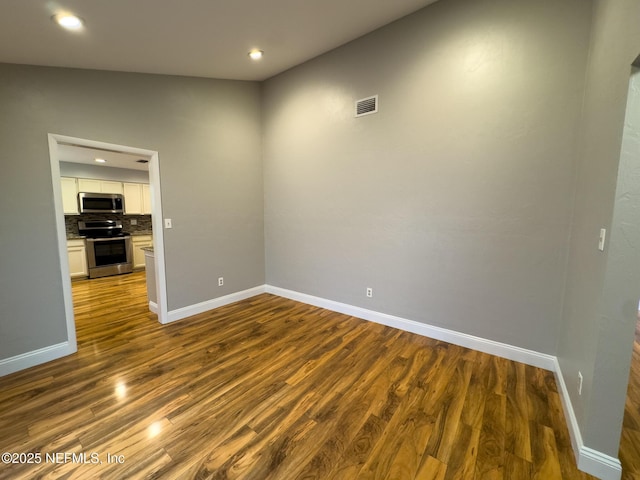 spare room with recessed lighting, dark wood-style floors, visible vents, and baseboards