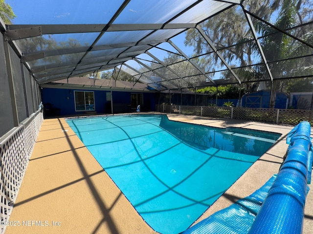 pool with glass enclosure, a patio area, and fence