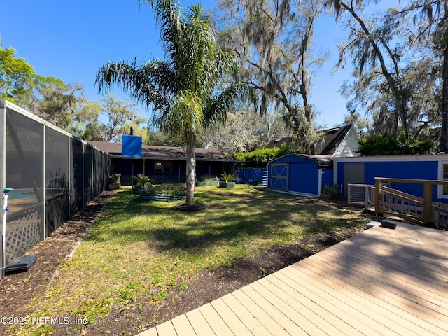 view of yard featuring a storage unit, a deck, an outbuilding, and a lanai