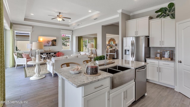 kitchen featuring a sink, stainless steel appliances, white cabinets, a raised ceiling, and open floor plan