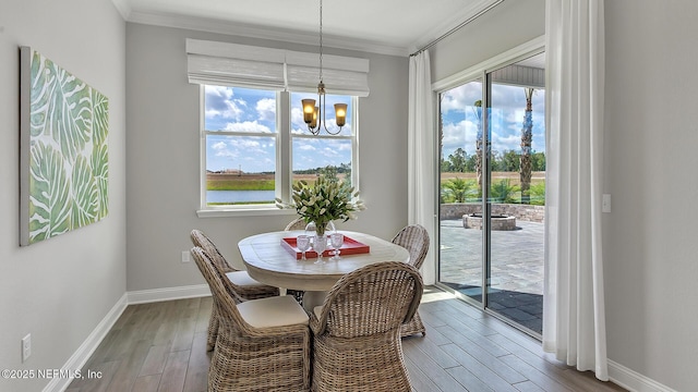 dining space featuring ornamental molding, baseboards, an inviting chandelier, and wood finished floors