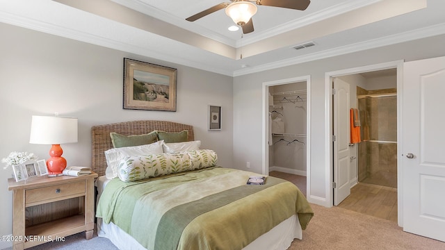 bedroom with a walk in closet, crown molding, a closet, and light carpet