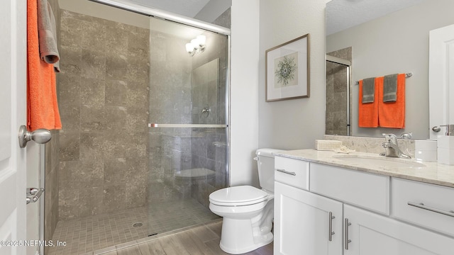 full bath featuring a stall shower, toilet, and vanity