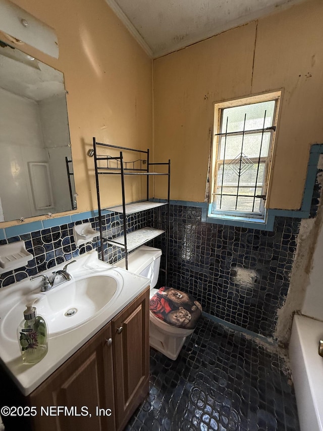 full bathroom with a washtub, toilet, vanity, wainscoting, and tile walls