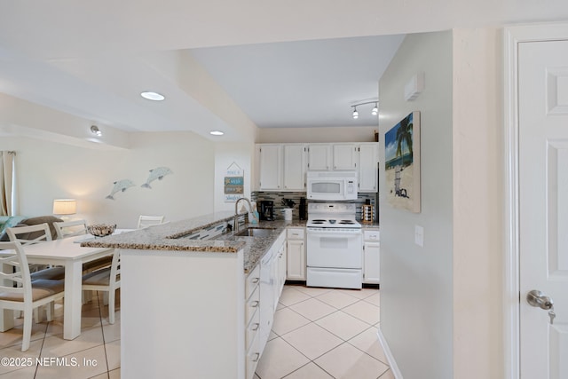 kitchen with white appliances, light tile patterned floors, stone counters, a peninsula, and a sink