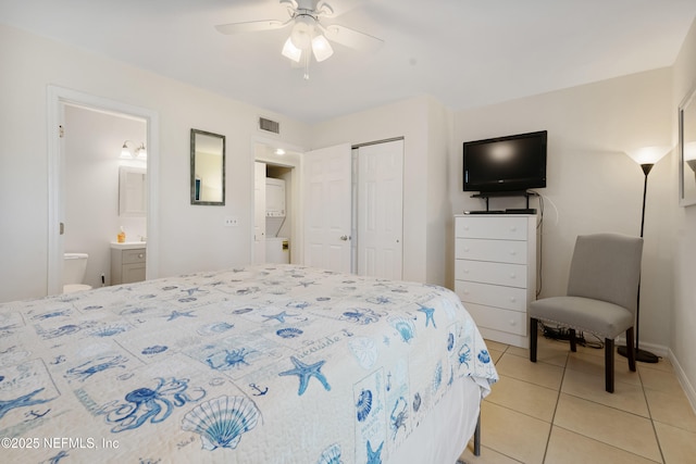 bedroom featuring visible vents, connected bathroom, baseboards, light tile patterned floors, and a closet