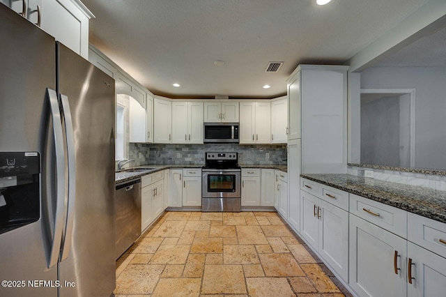 kitchen featuring visible vents, dark stone countertops, stone tile flooring, recessed lighting, and stainless steel appliances