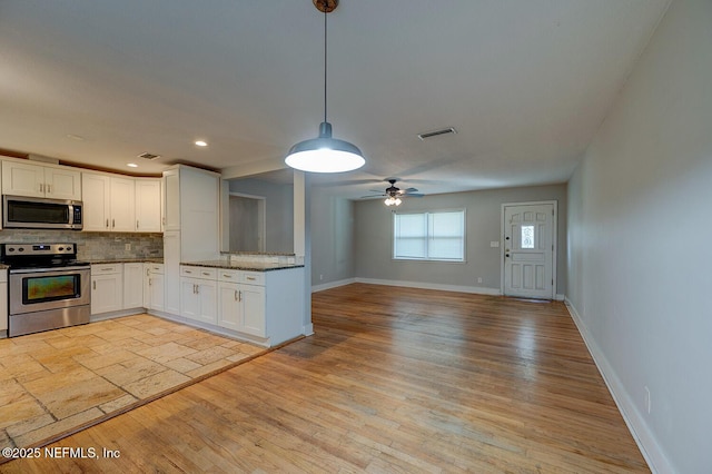 kitchen with white cabinets, tasteful backsplash, visible vents, and appliances with stainless steel finishes