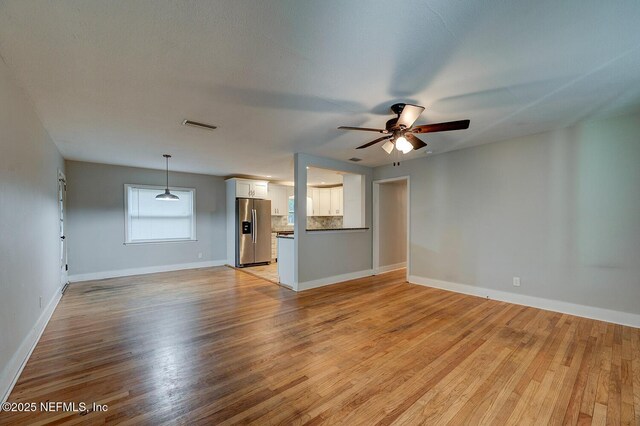 unfurnished living room with visible vents, baseboards, a ceiling fan, and light wood finished floors