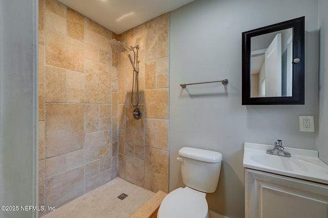 bathroom featuring toilet, vanity, and a tile shower