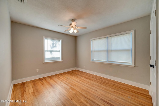 empty room with light wood-type flooring, baseboards, a textured ceiling, and a ceiling fan