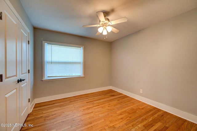 empty room with a ceiling fan, light wood-type flooring, and baseboards