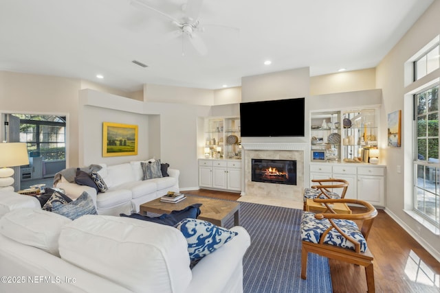 living room with visible vents, recessed lighting, a tile fireplace, and wood finished floors