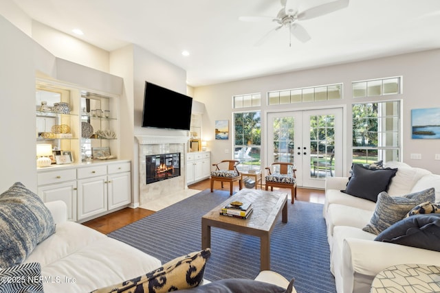 living room with recessed lighting, a premium fireplace, wood finished floors, and french doors