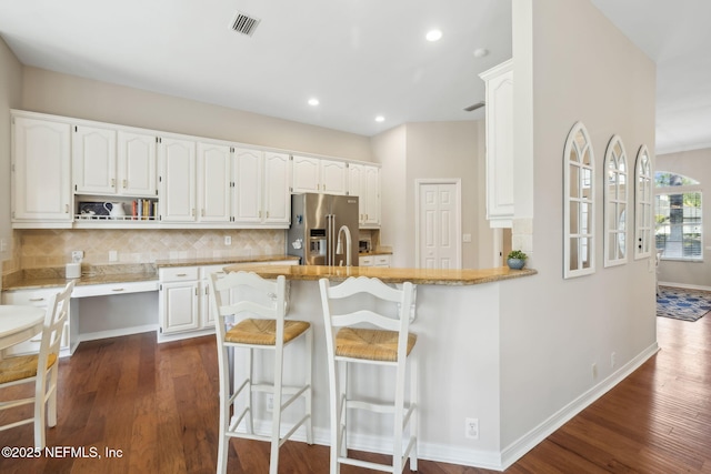 kitchen with dark wood finished floors, high end refrigerator, white cabinets, and decorative backsplash