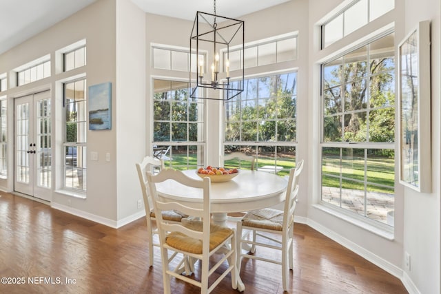 dining space featuring a chandelier, french doors, baseboards, and wood finished floors