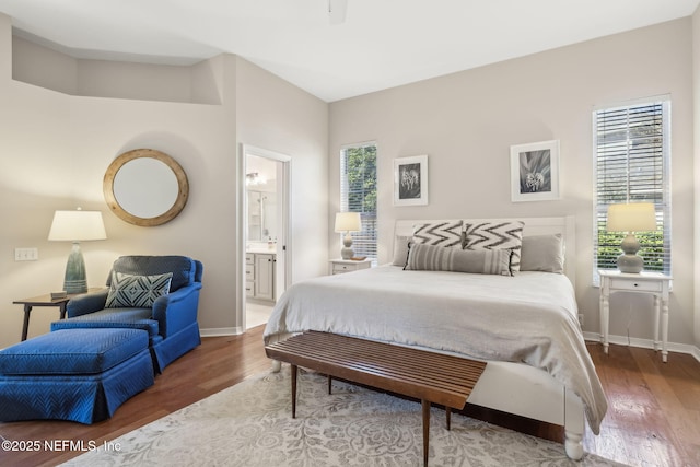 bedroom featuring connected bathroom, baseboards, and wood finished floors