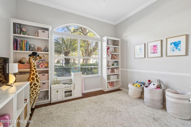 playroom with crown molding, baseboards, and wood finished floors