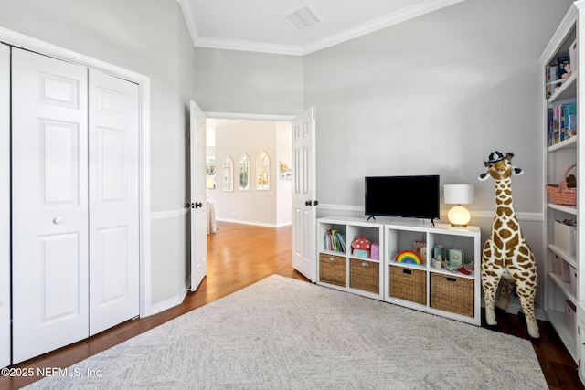 rec room with visible vents, baseboards, wood finished floors, and ornamental molding