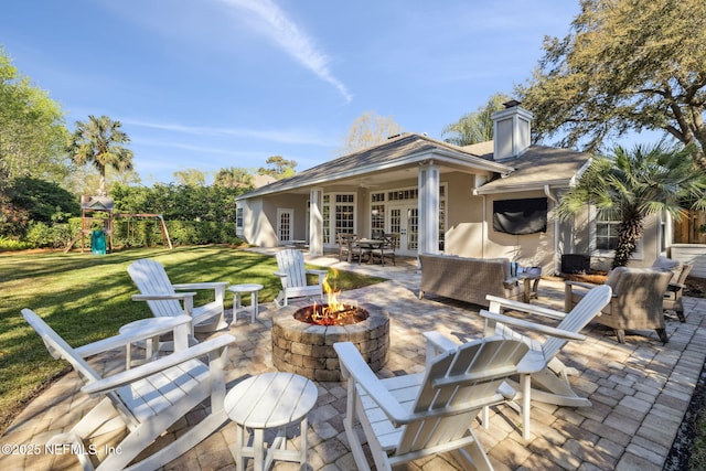 view of patio / terrace with an outdoor living space with a fire pit, a playground, and french doors