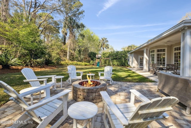 view of patio / terrace with a playground, a ceiling fan, and an outdoor fire pit