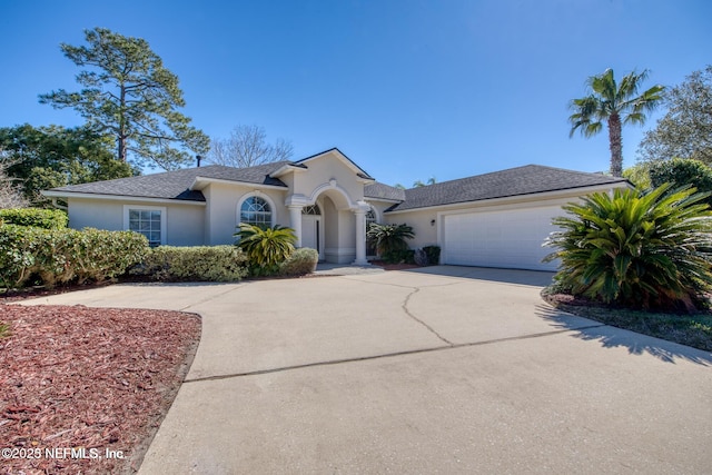 view of front facade with concrete driveway, an attached garage, and stucco siding