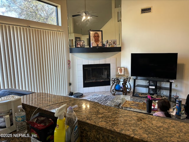 living area with visible vents, a high ceiling, ceiling fan, and a fireplace