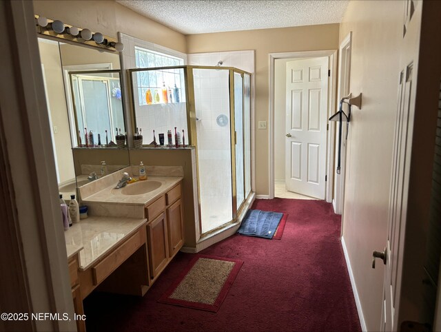 full bathroom with vanity, baseboards, a stall shower, and a textured ceiling