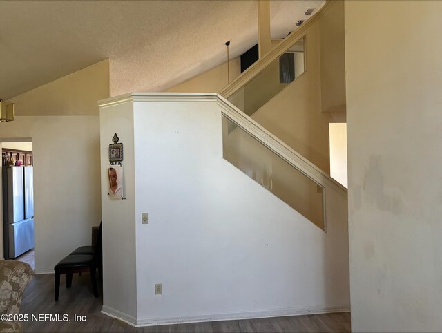 interior space with vaulted ceiling, baseboards, and wood finished floors