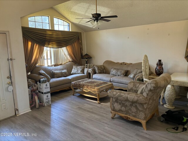 living area featuring vaulted ceiling, a textured ceiling, ceiling fan, and wood finished floors