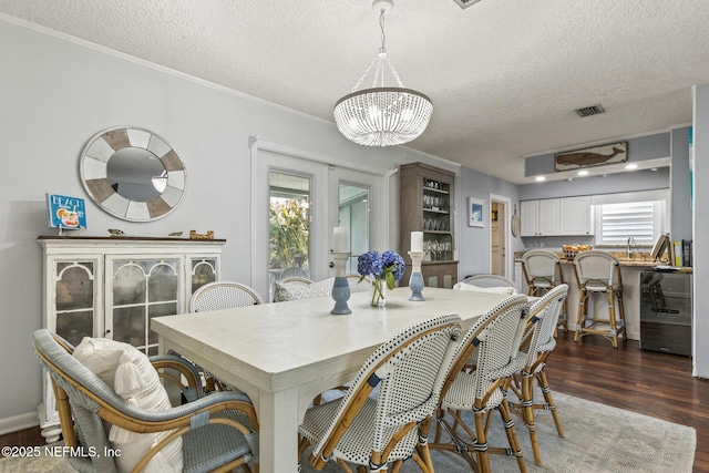 dining area featuring a chandelier, visible vents, dark wood finished floors, and crown molding