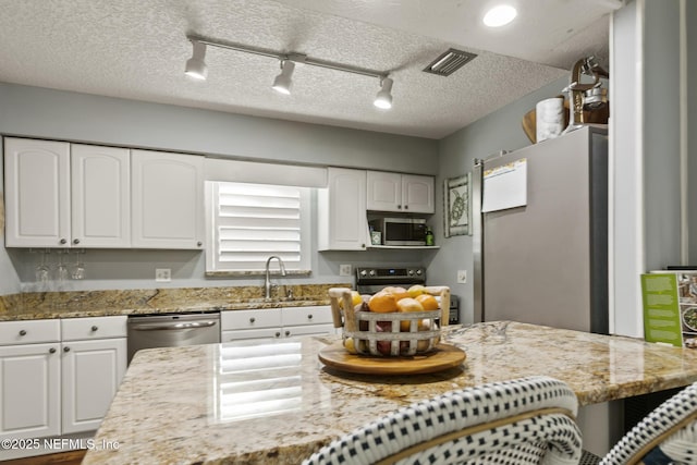 kitchen with a sink, white cabinets, visible vents, and stainless steel appliances