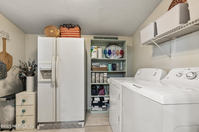 clothes washing area featuring light tile patterned floors, laundry area, washer and dryer, and a textured ceiling