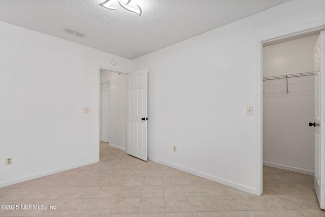 unfurnished bedroom featuring baseboards, visible vents, a spacious closet, a closet, and a textured ceiling