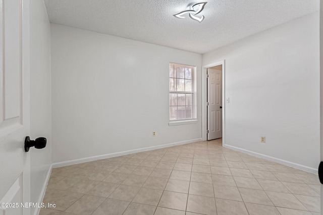 spare room with a textured ceiling and baseboards