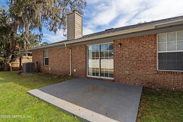 rear view of property featuring a yard, a patio area, brick siding, and a chimney