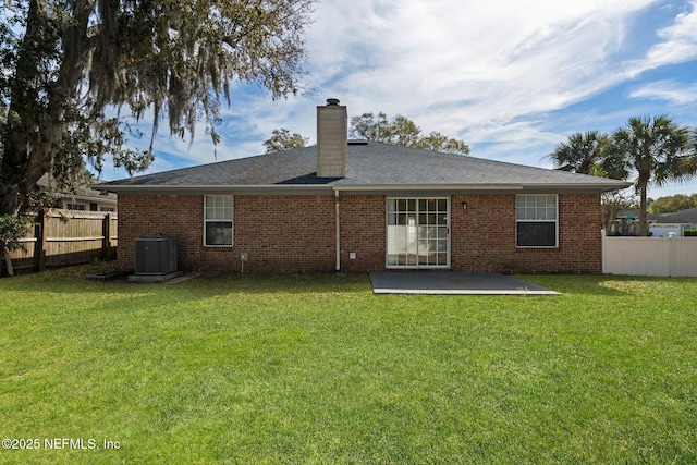 back of property featuring a yard, a chimney, fence private yard, and central AC