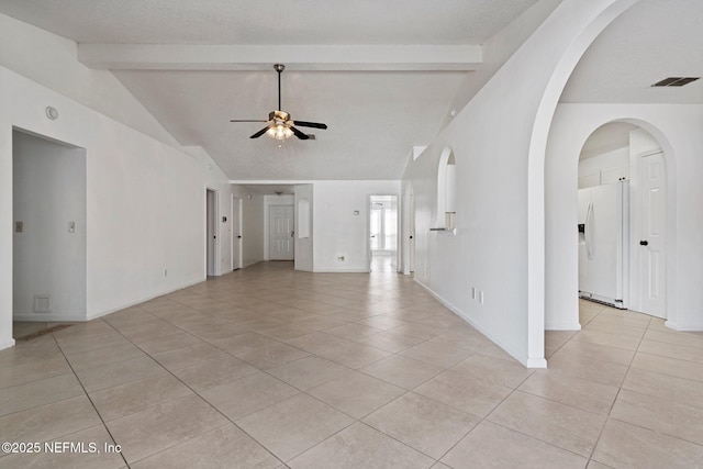 unfurnished living room with visible vents, lofted ceiling with beams, arched walkways, light tile patterned floors, and ceiling fan